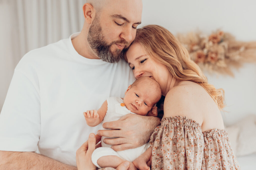 Inniger Moment: Eltern halten ihr Neugeborenes liebevoll im Arm – Newborn Shooting Würzburg