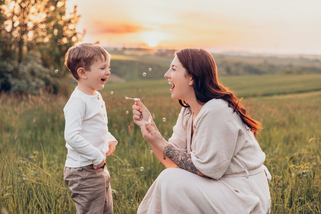 Mama hält ihr Kind im Arm bei Sonnenuntergang – natürliche Familienfotos Würzburg