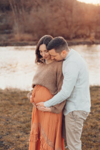 Schwangere Mama streichelt liebevoll ihren Bauch und schaut ihren Mann an, der auch den Bauch streichelt. Babybauchfotos Würzburg