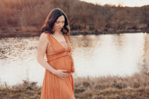 Schwangere Mama streichelt liebevoll ihrem Bauch an.. Babybauchfotos Würzburg
