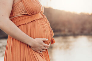Man sieht nur den schwangeren Bauch einer werdenden Mama in einem roten Bohokleid. Shooting Würzburg
