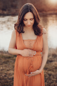 Schwangere Mama streichelt liebevoll ihrem Bauch an.. Babybauchfotos Würzburg